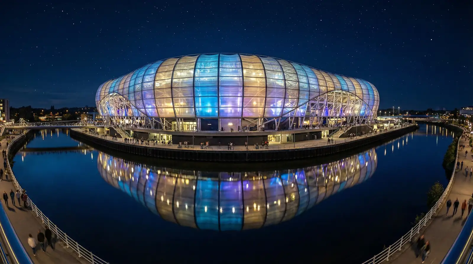 Exterior del Allianz Arena de Múnich iluminado de noche con reflejos en el agua circundante
