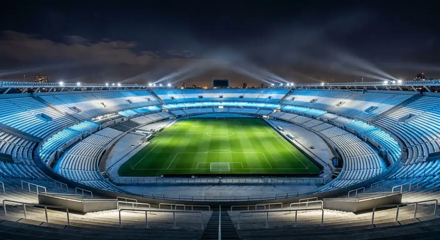 Futbola stadions naktī ar Argentīnas gaišzilbalto apgaismojumu un dramatisku prožektoru gaismu virs zaļā laukuma